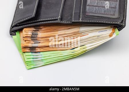 Una borsa nera trabocca di banconote e banconote in euro Foto Stock