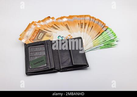 Ricchezza in una borsa con un fan di banconote in euro su uno sfondo bianco in studio Foto Stock