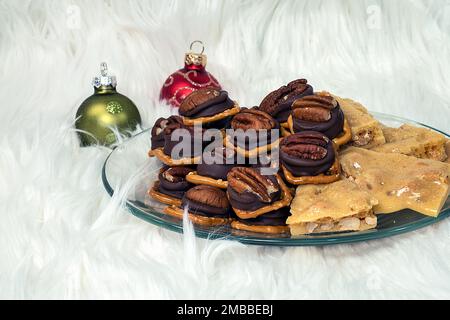 Il pretzel di arachidi e noci pecan si morde sulla pelliccia bianca con ornamenti natalizi Foto Stock