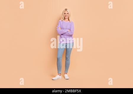 Foto a grandezza naturale di persona soddisfatta, con braccia incrociate, sorriso toothy isolato su sfondo di colore beige Foto Stock