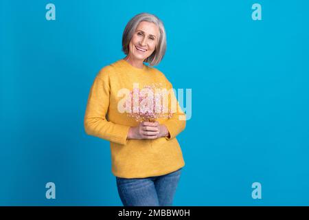 Foto di bella donna anziana mani tenere bouquet fiori selvatici isolato su sfondo di colore blu Foto Stock