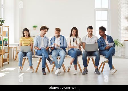 Gruppo di studenti che utilizzano i moderni dispositivi digitali durante la riunione Foto Stock