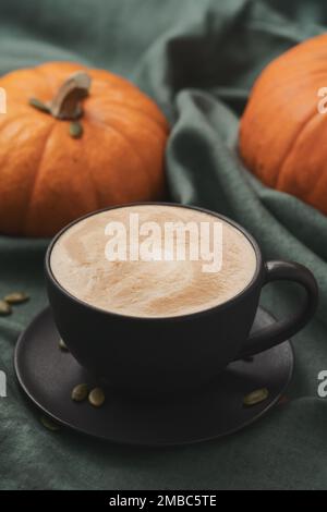 Latte piccante di zucca in tazza nera su tela linne, fuoco poco profondo Foto Stock