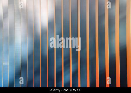 Astratto verticale con strisce nere e arancioni sulla superficie riflettente. Foto Stock