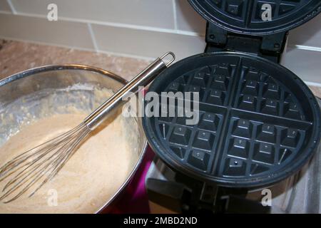 Mescolare i waffle in un recipiente accanto a un ferro da stiro per il brunch in una cucina residenziale sul piano superiore del banco. Foto Stock