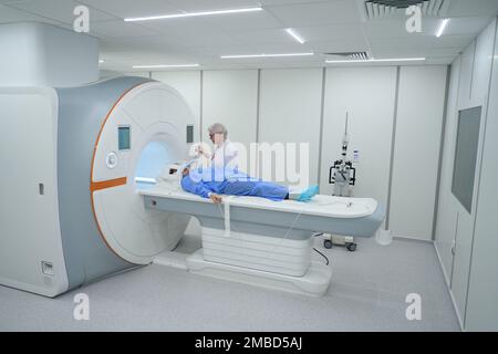 Donna diagnosticista esamina un paziente su una macchina MRI Foto Stock