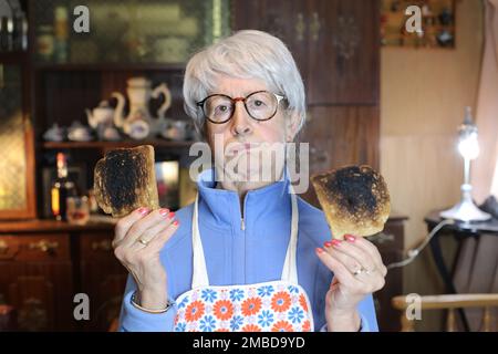 Donna anziana delusa che tiene brostini bruciati Foto Stock