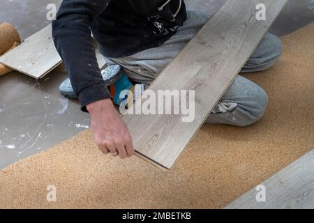 Un uomo posa un pavimento laminato. Riparazione in appartamento. Pavimento laminato installato in modo professionale Foto Stock