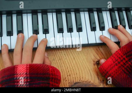 le mani del ragazzo suonano la tastiera giocattolo del pianoforte a casa Foto Stock