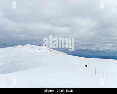 Due escursionisti a Kralova Hola in Slovacchia, bassa Tatra montagne durante l'inverno torre TV cielo nuvoloso cresta montagna Foto Stock