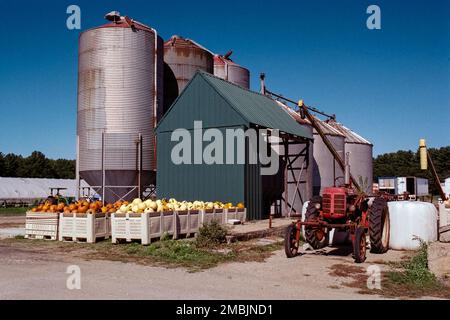 Silo di grano e trattore rosso vintage contro un cielo blu intenso sulla Spring Brook Farm a Littleton, Massachusetts. L'immagine è stata acquisita su pellicola a colori analogica Foto Stock
