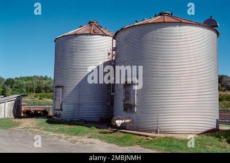 Due grandi silos metallici con un cielo pigstico e blu sullo sfondo presso la Spring Brook Farm di Littleton, Massachusetts. L'immagine è stata acquisita su colo analogico Foto Stock