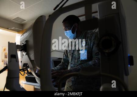 Senior Airman Denzel Wilson, 15th tecnico optometrico di Squadron di preparazione medica operativa, opera una macchina fotografica retinica presso la clinica di optometria alla base congiunta Pearl Harbor-Hickam, Hawaii, 16 giugno 2022. Gli esami oculari e le fotografie dettagliate della retina documentano e tengono traccia dei cambiamenti di salute degli occhi nel corso degli anni. Foto Stock