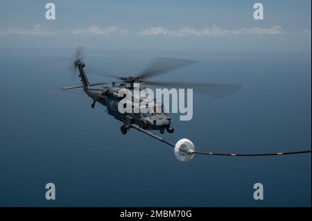 Un elicottero HH-60G Pave Hawk viene rifornito da un 39th Rescue Squadron HC-130J Combat King II durante una gara di tiro al tacchino al largo della costa della Florida il 16 giugno 2022. Durante il concorso, i membri dell'equipaggio hanno gareggiato su abilità come l'impiego di armi da aerei, il rifornimento di aerei da elicotteri, la navigazione degradata, la ricerca degradata e il sollevamento confinato. Foto Stock