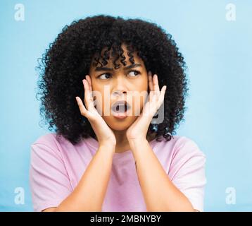Shock, sorpresa faccia e donna nera con sfondo isolato blu in uno studio. WOW, pensare e le mani di un giovane che sente un segreto o. Foto Stock