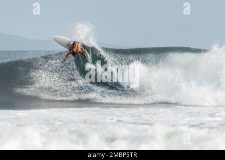 Surf a Keramas Beach, Bali, Indonesia, uomo e donna surf onde con un surf board, imparare surf a Kuta e Uluwatu Foto Stock