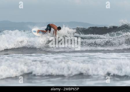 Surf a Keramas Beach, Bali, Indonesia, uomo e donna surf onde con un surf board, imparare surf a Kuta e Uluwatu Foto Stock