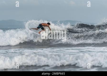 Surf a Keramas Beach, Bali, Indonesia, uomo e donna surf onde con un surf board, imparare surf a Kuta e Uluwatu Foto Stock