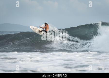 Surf a Keramas Beach, Bali, Indonesia, uomo e donna surf onde con un surf board, imparare surf a Kuta e Uluwatu Foto Stock