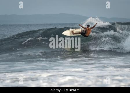 Surf a Keramas Beach, Bali, Indonesia, uomo e donna surf onde con un surf board, imparare surf a Kuta e Uluwatu Foto Stock