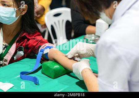 Un infermiere sta usando un ago per prelevare il sangue per un esame al controllo sanitario annuale. Foto Stock