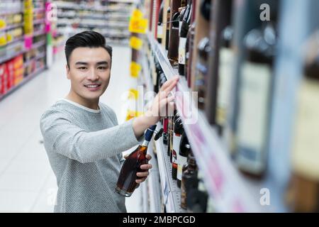 Un giovane uomo che fa shopping nel supermercato Foto Stock