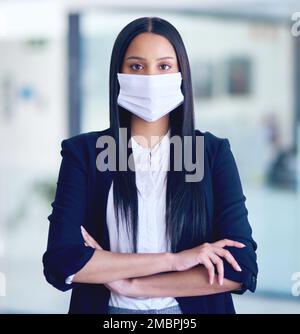 Siate consapevoli, fate attenzione. Ritratto di una giovane donna d'affari che indossa una maschera facciale in un ufficio moderno. Foto Stock