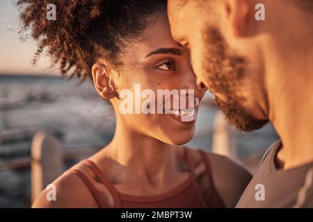 Coppia nera, sorridi e abbraccia con la fronte abbracciando il rapporto, la compassione o l'amore e la cura presso la spiaggia. Felice uomo e donna che toccano le teste sorridendo Foto Stock