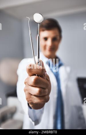 Un super dentista utilizza super strumenti. Ritratto di una giovane donna che tiene attrezzi dentali nel suo ufficio. Foto Stock