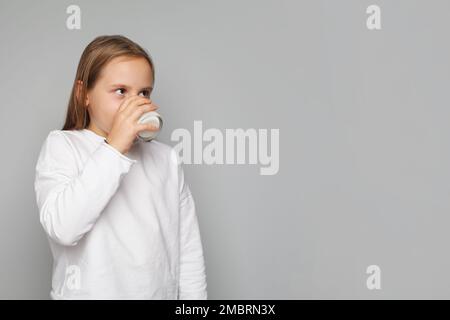 Bambina che beve un latte su sfondo bianco Foto Stock