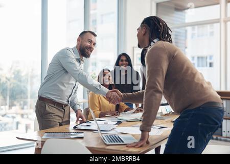Benvenuto nel team. due bei uomini d'affari che scuotono le mani durante una riunione in ufficio durante il giorno. Foto Stock