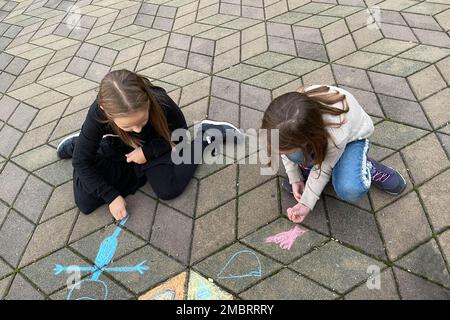 Bambini giovani ragazze disegno con gessi colorati all'aperto. Attività ricreative all'aperto per bambini Foto Stock