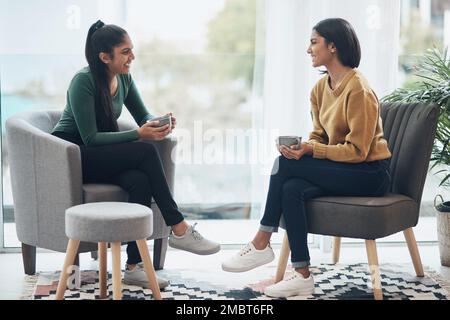 Passare del tempo con mia sorella è l'unica terapia di cui ho bisogno. due giovani donne bevono caffè mentre si siedono insieme a casa. Foto Stock