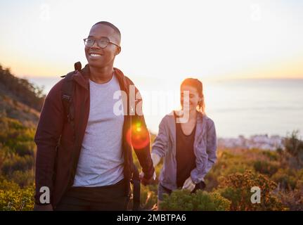 Coppia interrazziale, allenamento e trekking esercizio al tramonto su una montagna come fitness mattutino in natura. Gente felice, uomo e donna in un rapporto Foto Stock