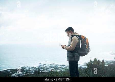 Creazione di tutti i tipi di connessioni. un giovane uomo che usa un cellulare mentre fuori su un'escursione. Foto Stock