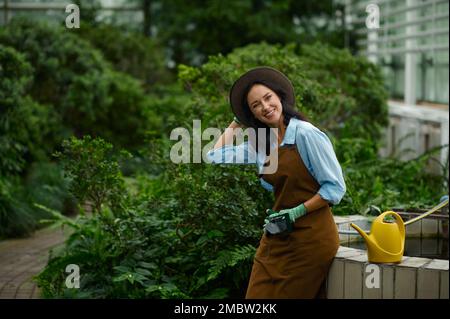 Giovane donna giardiniera orgogliosa della bellezza della propria serra Foto Stock