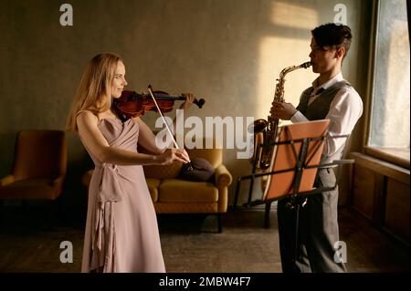 Giovane violinista e sassofonista maschile in casa Foto Stock