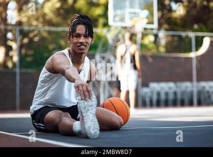Aspiro a diventare come i grandi. Ritratto di un giovane sportivo che allunga le gambe su un campo da basket. Foto Stock