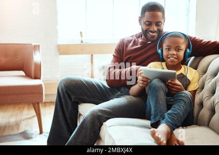 Tablet, divano e padre con suo figlio che guarda un divertente, fumetto o meme video sui social media. Felice, sorriso e uomo africano in streaming un film con il suo Foto Stock
