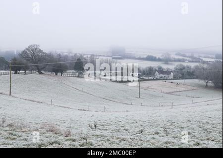 Drakelow, Worcestershire, 21 gennaio 2023 - Una casa di campagna in stile tudor situata in una valle vicino a Drakelow, Worcestershire, è circondata da campi ghiacciati e bassa nebbia gelida quando le temperature precipitarono ancora una volta durante la notte. Credito: Interrompi stampa Media/Alamy Live News Foto Stock