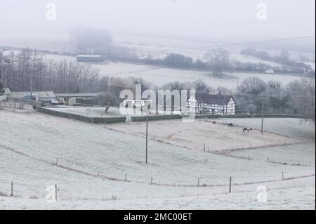 Drakelow, Worcestershire, 21 gennaio 2023 - Una casa di campagna in stile tudor situata in una valle vicino a Drakelow, Worcestershire, è circondata da campi ghiacciati e bassa nebbia gelida quando le temperature precipitarono ancora una volta durante la notte. Credito: Interrompi stampa Media/Alamy Live News Foto Stock