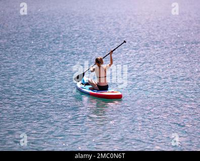 Villach, Austria - 2022 settembre 4 : giovane donna bionda che va in canoa su un lago panoramico in un pomeriggio estivo, Faaker See Foto Stock