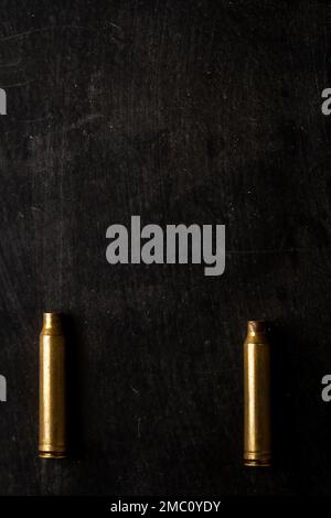 Cartucce pallottola del fucile vuote giacenti su sfondo nero. Foto Stock