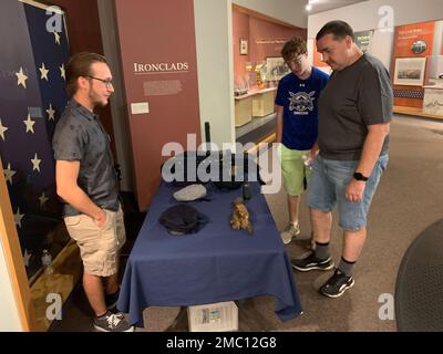 Ethan Dykes, un internista al museo navale di Hampton Roads, si impegna con i visitatori nella galleria della Guerra civile del museo su manufatti e oggetti associati alla USS Cumberland. Cumberland affondò durante un fidanzamento con il montone confederato, CSS Virginia il 8 marzo 1862. Il museo è il deposito ufficiale per i manufatti recuperati dal sito del relitto della USS Cumberland. Foto Stock