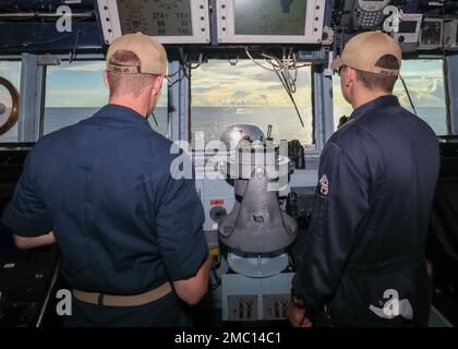 MARE DELLE FILIPPINE (23 giugno 2022) la firma di Christopher Rielage, a sinistra, da Fairfax, Virginia, e di Ensign Benjamin Freund, a destra, da Old Westbury, New York, monitorano il percorso della nave dal pilothouse a bordo di un cacciatorpediniere missilistico guidato di classe Arleigh Burke USS Benfold (DDG 65). Benfold viene assegnato al Comandante, Task Force (CTF) 71/Destroyer Squadron (DESRON) 15, il più grande DESRON della Marina e la principale forza di superficie della flotta statunitense 7th. Foto Stock