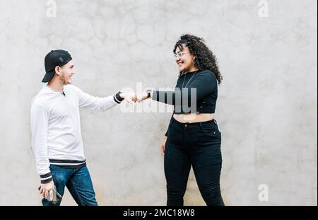 Due amici adolescenti che urlano i pugni. Un tipo e una ragazza adolescente che scuotono i pugni l'un l'altro, primo piano di due amici divertenti che urtare pugni pugni in un Foto Stock