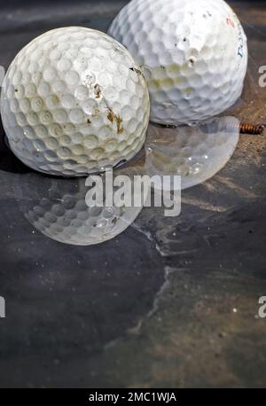 vecchie palle da golf che riposano in una pozza d'acqua sporca Foto Stock