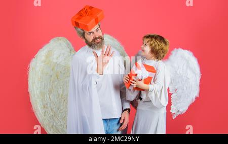 San Valentino. Padre in costume d'angelo e piccolo figlio in ali angeliche con presente. Angeli carini. Foto Stock