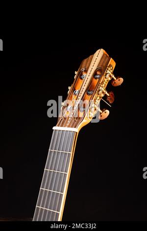 Dettaglio della testa della chitarra classica isolato su sfondo nero. Chitarra acustica classica. Perfetto per volantini, biglietti, poster o sfondi Foto Stock