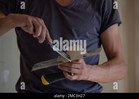 Un uomo tiene in mano una spatola con stucco. Messa a fuoco selettiva. costruzione Foto Stock